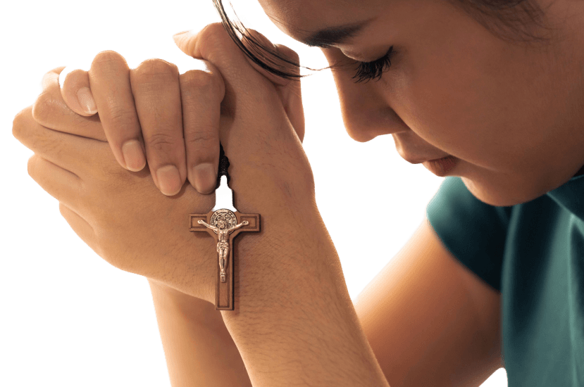 Person praying with cross necklace